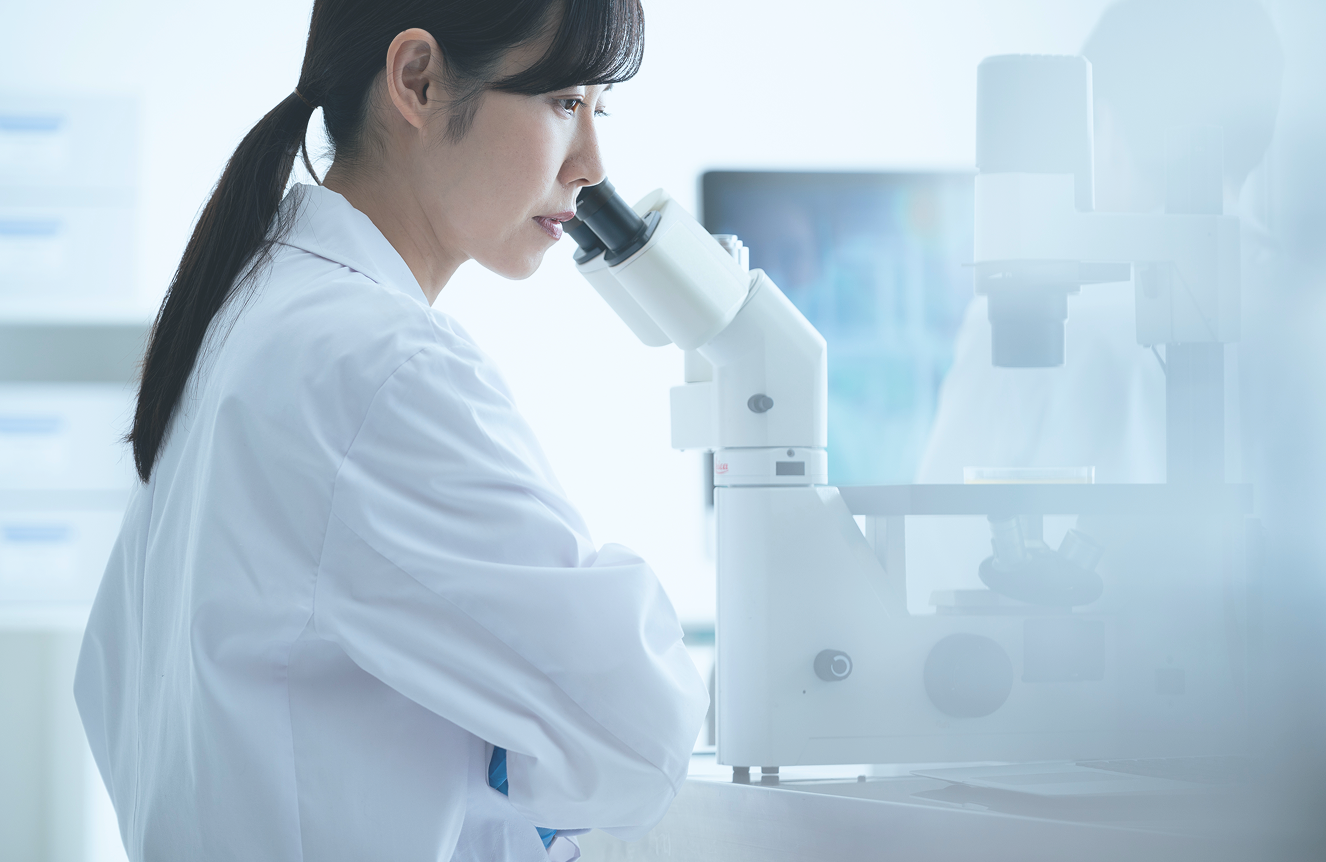 顕微鏡で観察する女性研究者の写真